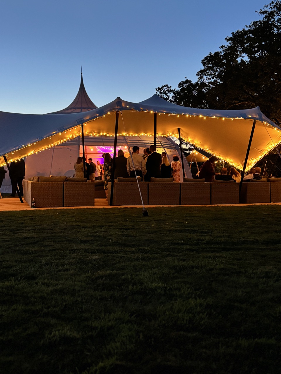 Evening outdoor event under illuminated marquee tent